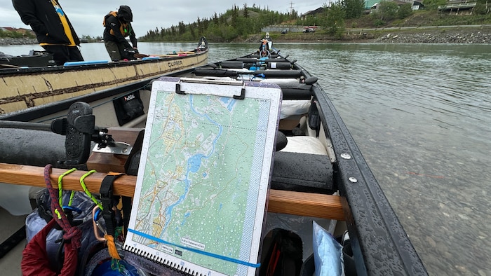 Un canot remplis de bagages avec la carte d'une rivière en avant-plan.