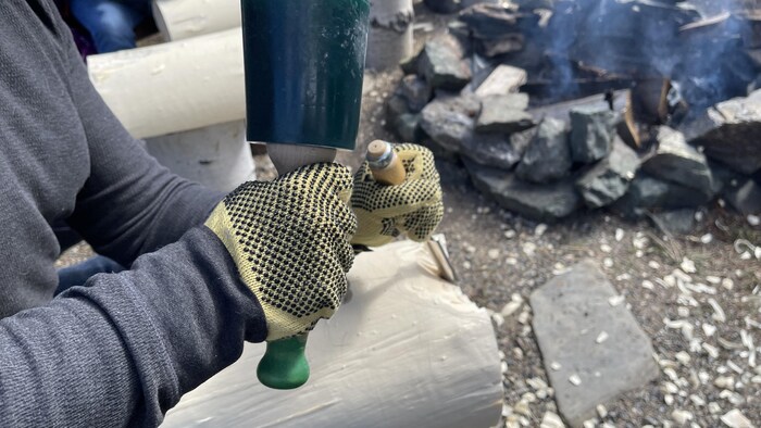 Une personne avec un maillet et un ciseau de sculpture.