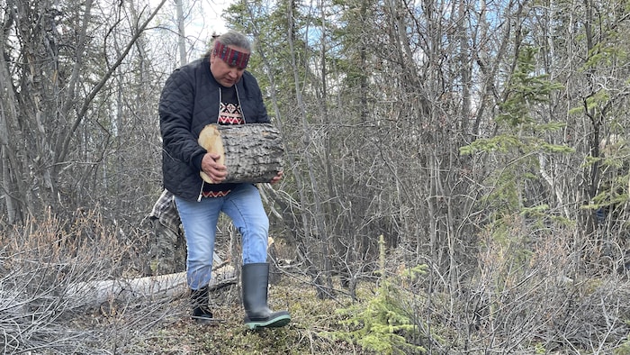 Marcel Pelletier transporte une bûche à Ross River au mois de mai 2026.