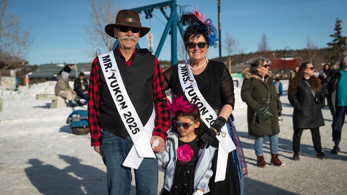 Un couple et un enfant avec des banderoles de M. et Mme Yukon, le 21 février 2025. 