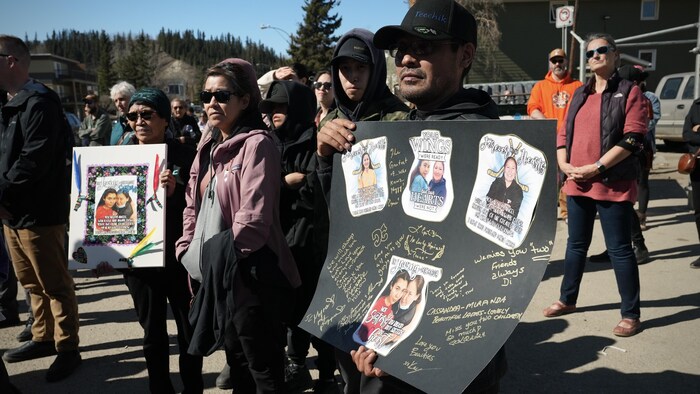 Un homme tient une pancarte décorée des photos des victimes, le 26 avril 2024.