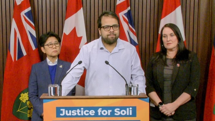 Yusuf Faqiri parle aux journalistes derrière un podium devant Kristyn Wong-Tam et Emilie Coyle.