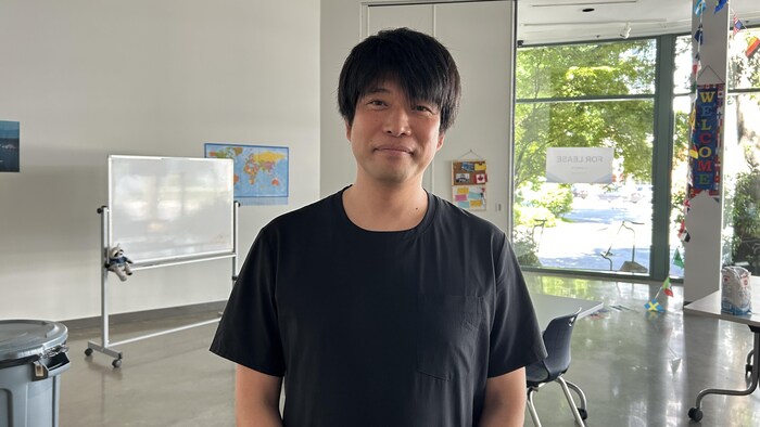 Yusuke Shibata est devant son œuvre, qui consiste en la reproduction d'une salle de classe.