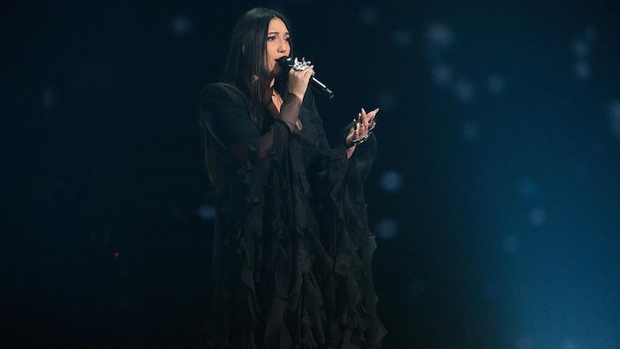 Une femme vêtue de noir chante.