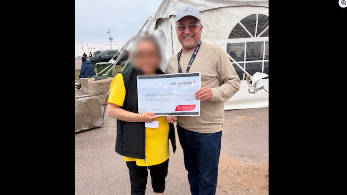 Yves Côté remet un chèque d'Air Liaison devant une tente.