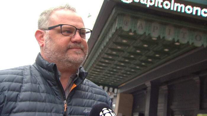 Yves Doucet sur le trottoir sous l'enseigne du Capitol.