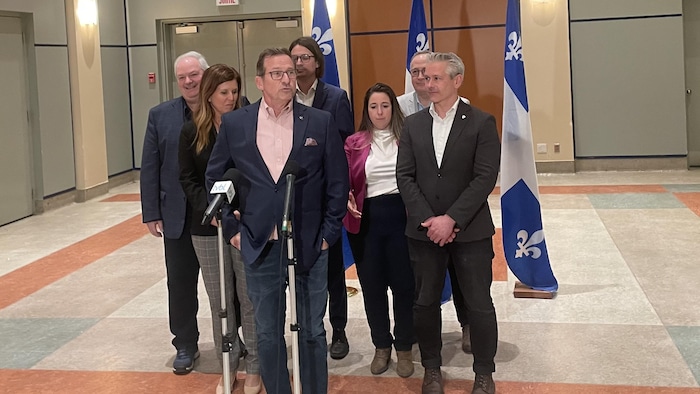 Yves-François Blanchet et des candidats devant des micros.