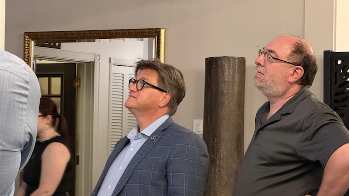 Yves Montigny et un militant regardent, la mine basse, les résultats des élections. 