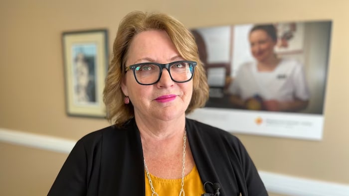Yvette Coffey pose pour une photo. Elle est dans un corridor de ce qui semble être un centre de soins.