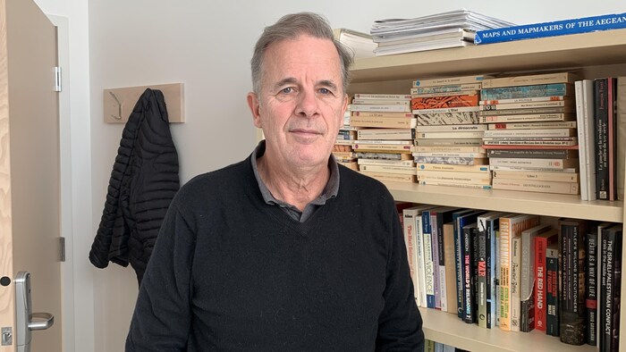 Yvon Grenier devant une étagère remplie de livres.