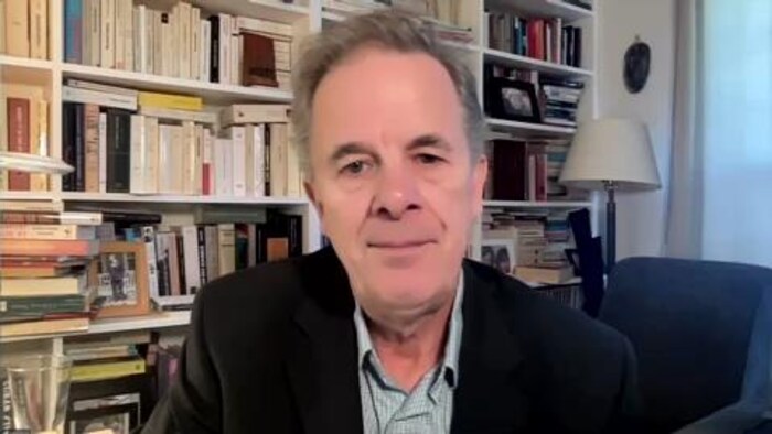 Yvon Grenier devant une bibliothèque remplie de livres.