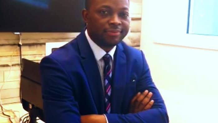 Yvon Muya Cimanga pose pour une photo les bras croisés et assis.