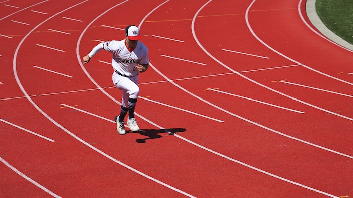 Habillé en uniforme de baseball, il court sur la piste d'athlétisme