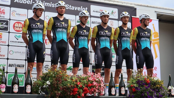 Six jeunes cyclistes prennent une photo d'équipe sur une scène dans les couleurs de Crabbé-dstny