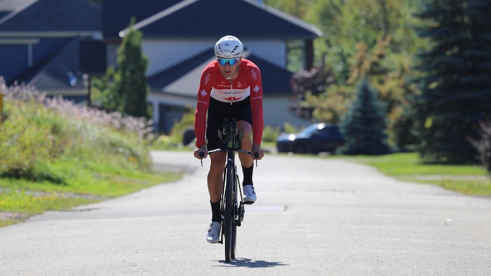 Il pédale dans une rue boisée vêtu de sa combinaison de l'équipe canadienne. 