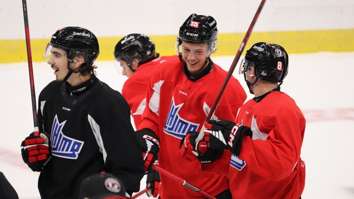 Des hockeyeurs rient sur la patinoire à l'entraînement.