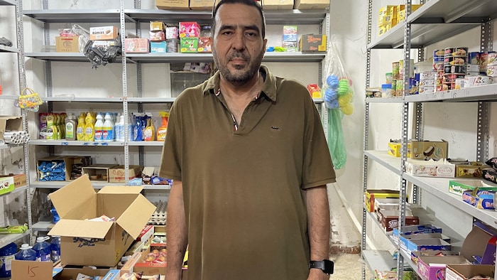 Un homme portant une chemise brune regarde la caméra.