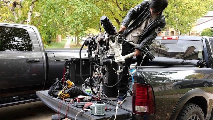 Zekun Wang manipule une machine dans la boîte d’une camionnette.