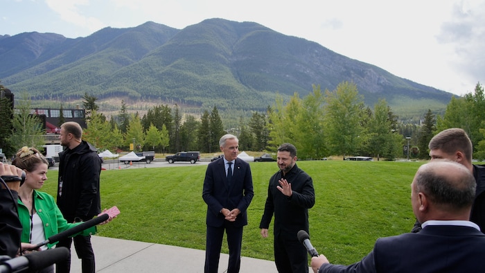 Des journalistes entourent le premier ministre canadien Mark Carney et le président ukrainien Volodymyr Zelenskiy à l'issue d'une réunion du Cabinet du gouvernement fédéral à Banff, en Alberta.