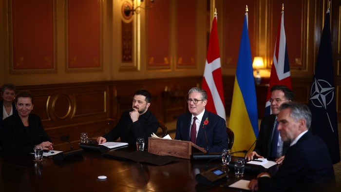 Keir Starmer, entouré de Volodymyr Zelensky et Mark Rutte, assis autour d'une grande table de réunion où l'on trouve aussi Mette Frederiksen et Dick Schoofla.
