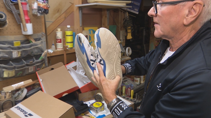 Zénon Chiasson montre une paire de tennis abimée par lad petit-fils au cours de ses matchs.