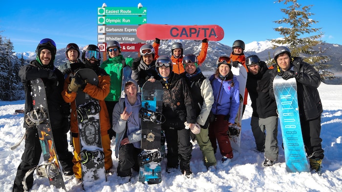 Des jeunes avec des planches à neiges sur une montagne.