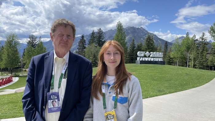 Un homme et une femme posant sur un terrain destiné au G7, les Rocheuses en arrière-plan.