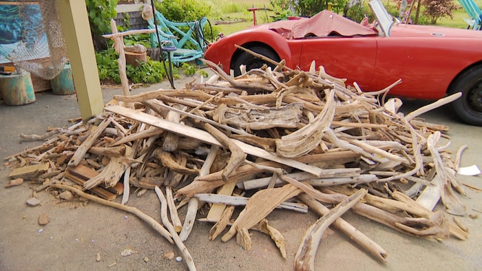 A mountain of pieces of beach wood next to a convertible Cadillac. Furthermore, he sculpts giant he sculpts giant birds beach new birds beach