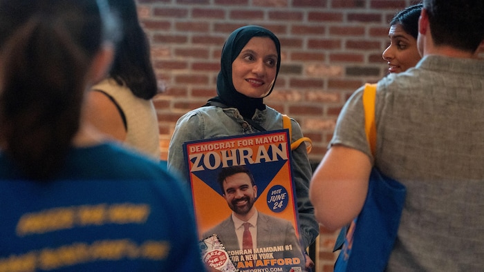 A supporter of the Democratic candidate Zohran Mamdani holds a poster in his favor in her hands.