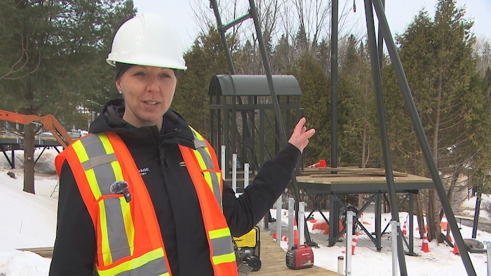Une femme avec un casque de construction montre l'ampleur des travaux.