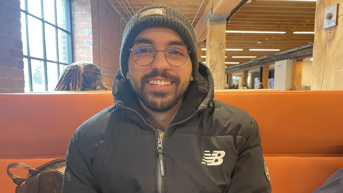 Zouhair Sajid est assis sur un banc avec un dossier orange.