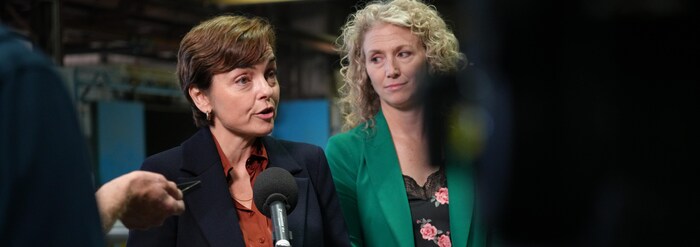 Christine Fréchette s'exprime au micro, les mains ouvertes, à côté d'une femme en veste verte.