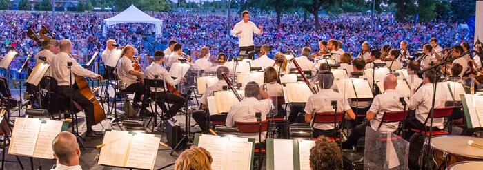 On voit des musiciens et musiciennes sur une scène devant public.