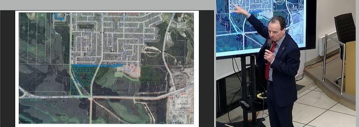 Serge Allard pointe une carte de Val-d'Or du doigt en parlant au micro.