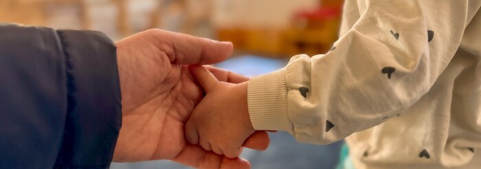 Un papa tient la main de sa petite fille. 