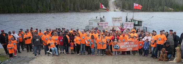 Un regroupement de personnes se tient devant le traversier.
