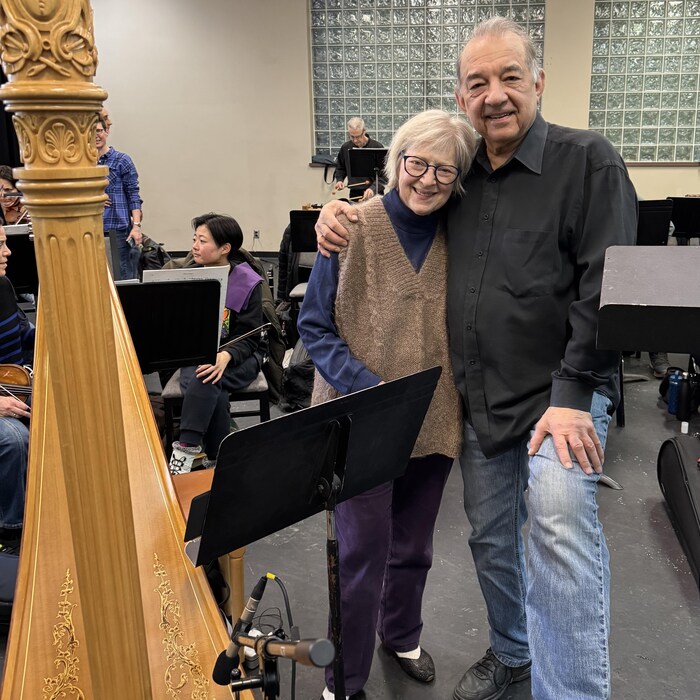 Deux personnes face à l'objectif dans une salle de répétition de concert. 