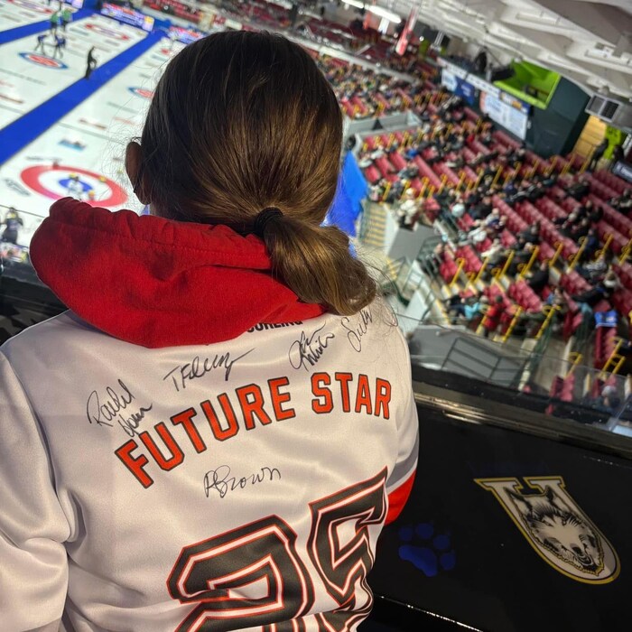 Une jeune femme regarde une partie de curling.