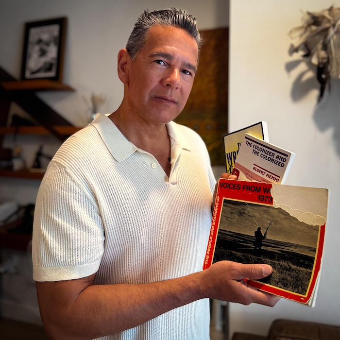 Taiaiake Alfred tient trois livres dans ses mains.