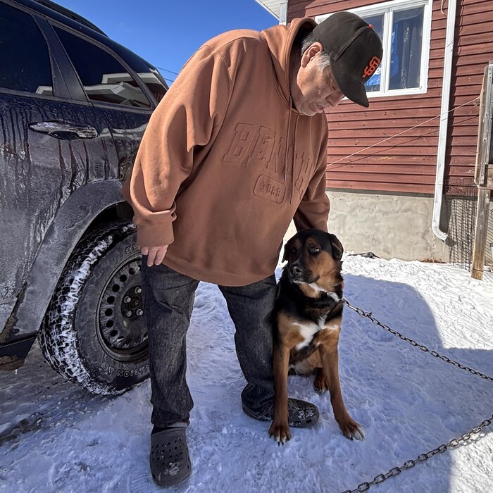 Richard Vollant caresse son chien qui se tient près de lui.