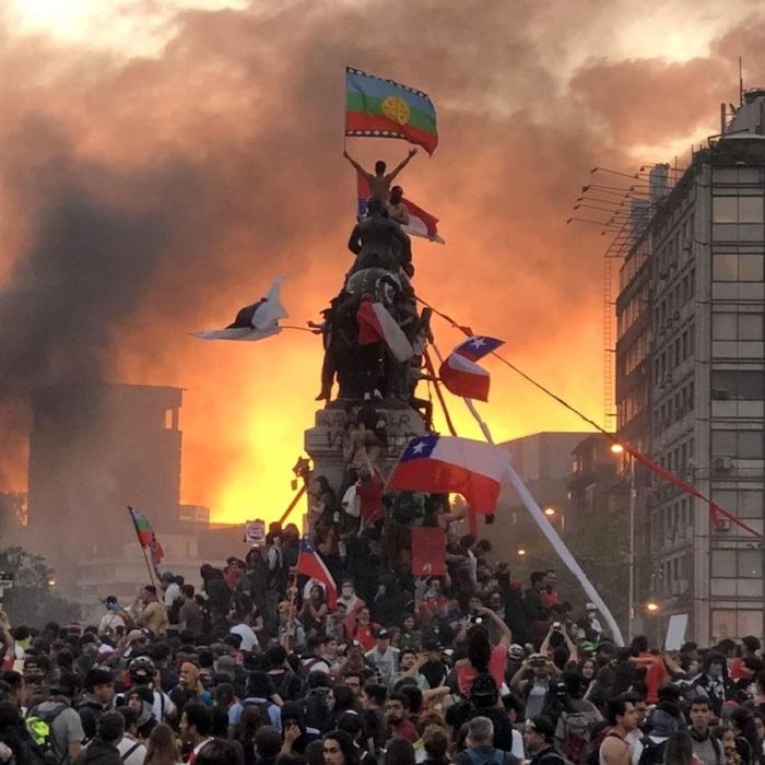 Une marre de manifestant grimpant à une statue à Santiago au Chili.