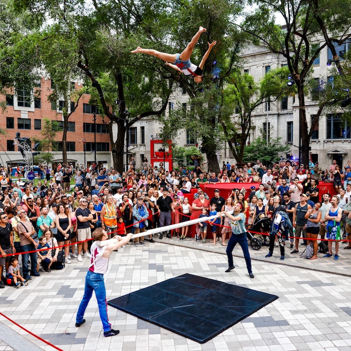 Trois artistes de cirque se produisent au milieu d'une foule.