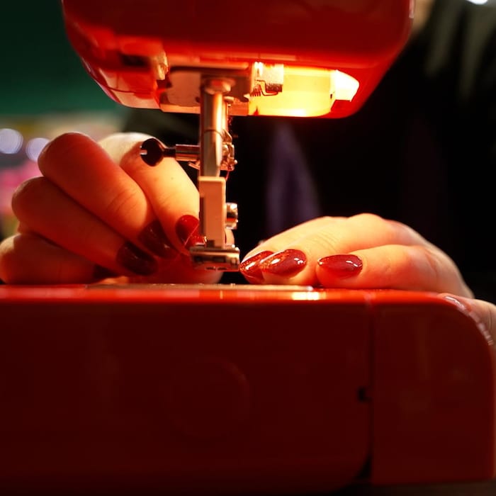 Une machine à coudre avec les mains d'une personne qui l'utilise.  