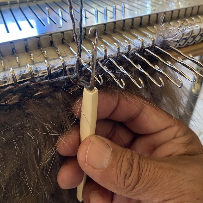 Un gros plan de la main de D’Arcy Moses, qui tient un crochet à tricoter.