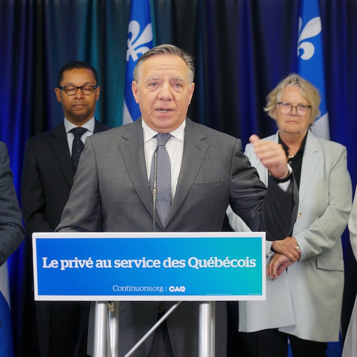 François Legault est derrière un podium, sur lequel on peut lire « Le privé au service des Québécois ». 