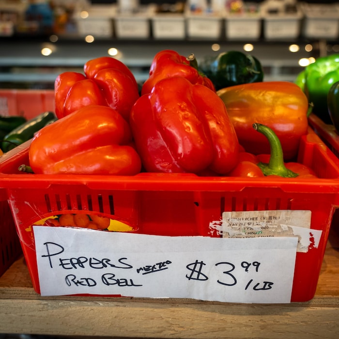 Des poivrons dans un bac avec une étiquette affichant le prix à 3,99 dollars le livre, sur un étalage d'épicerie, en Colombie-Britannique.