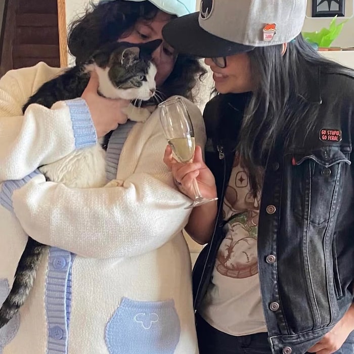 Deux femmes ensemble, l'une tenant un chat et l'autre un verre de champagne.