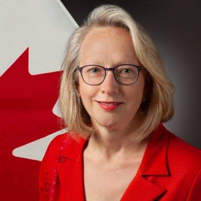 Jennifer May pose pour une photo devant un drapeau du Canada.