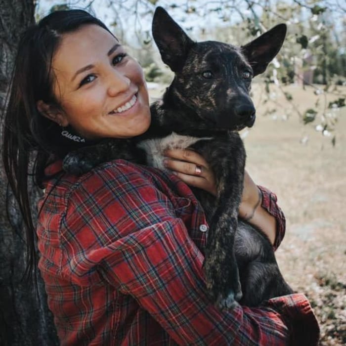 Une femme porte un chien dans ses bras.