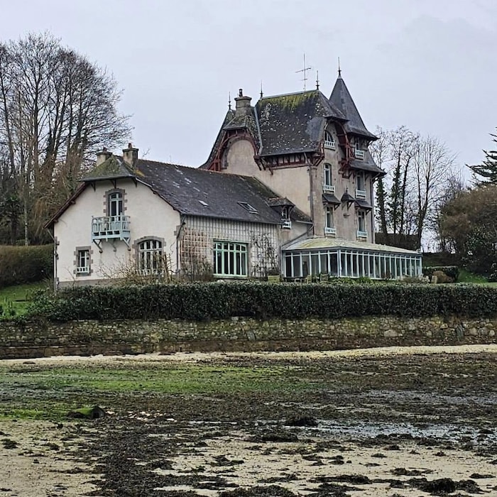 Une vieille maison borde une plage.